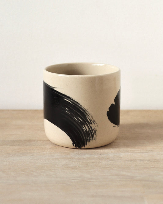 Brush-Stroked Clear Cup – handmade wheel-thrown white stoneware cup with expressive black brushstrokes and a clear glaze, crafted in Amsterdam by Zeyah Ceramics.