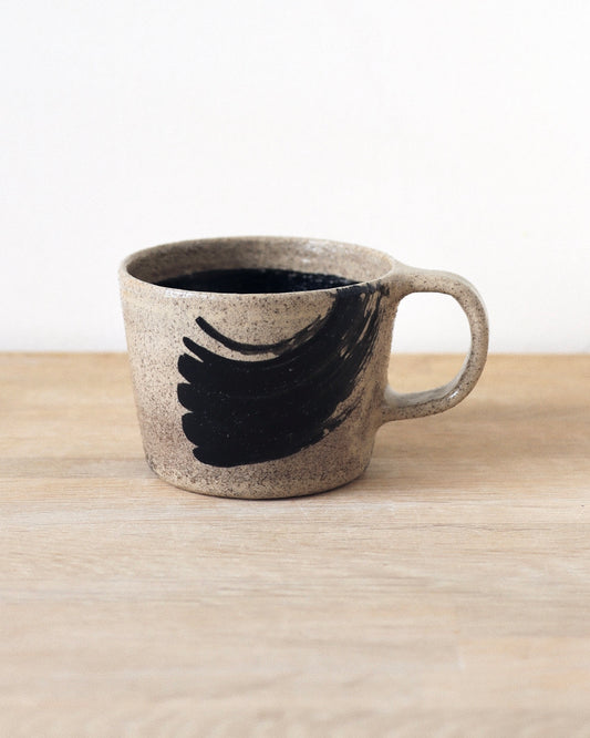 Grey Brush-Stroked Cup – handmade grey speckled stoneware cup with black brushstrokes and clear glaze revealing groggy texture, crafted in Amsterdam.