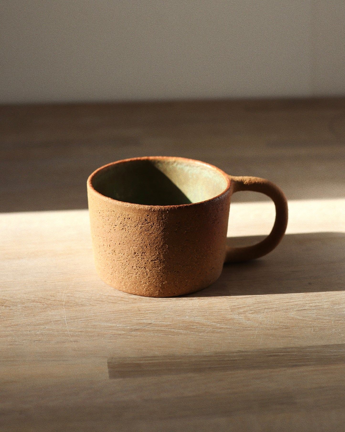 Rhea Mug – handmade red grogged stoneware mug with textured unglazed exterior and deep green glazed interior, crafted in Amsterdam by Zeyah Ceramics.