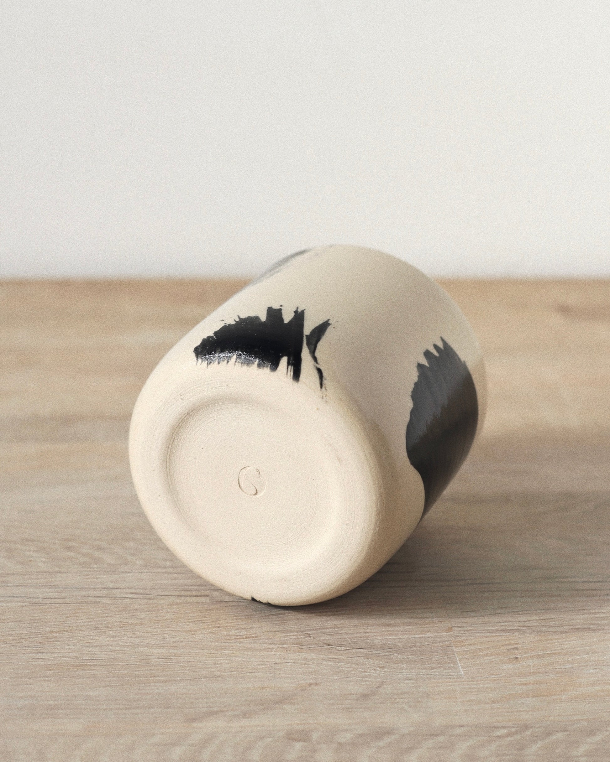 Brush-Stroked Clear Cup – handmade wheel-thrown white stoneware cup with expressive black brushstrokes and a clear glaze, crafted in Amsterdam by Zeyah Ceramics.