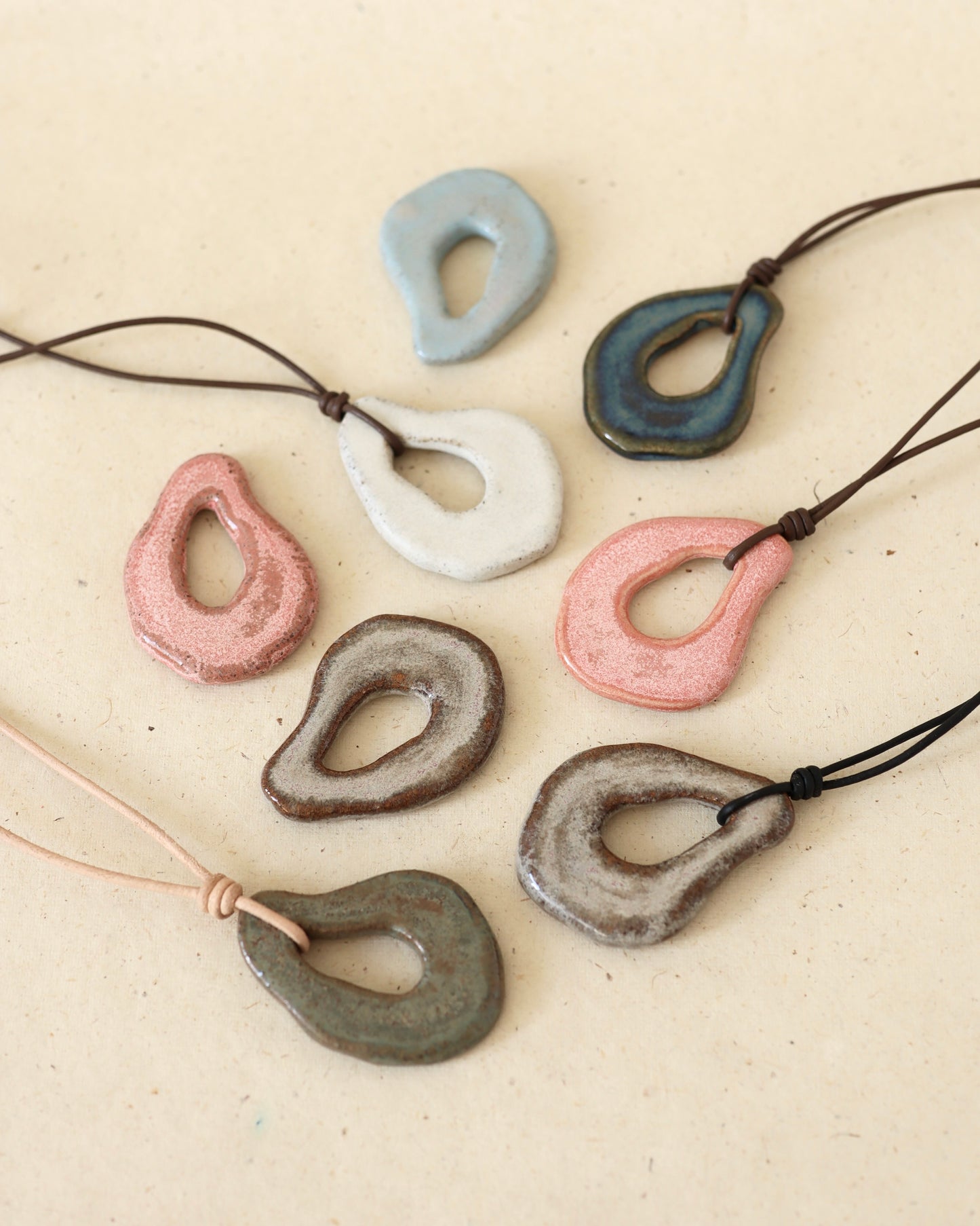 Hand-shaped, ceramic, light grey speckled stoneware amulet in a green, showing subtle speckling and smooth contours.