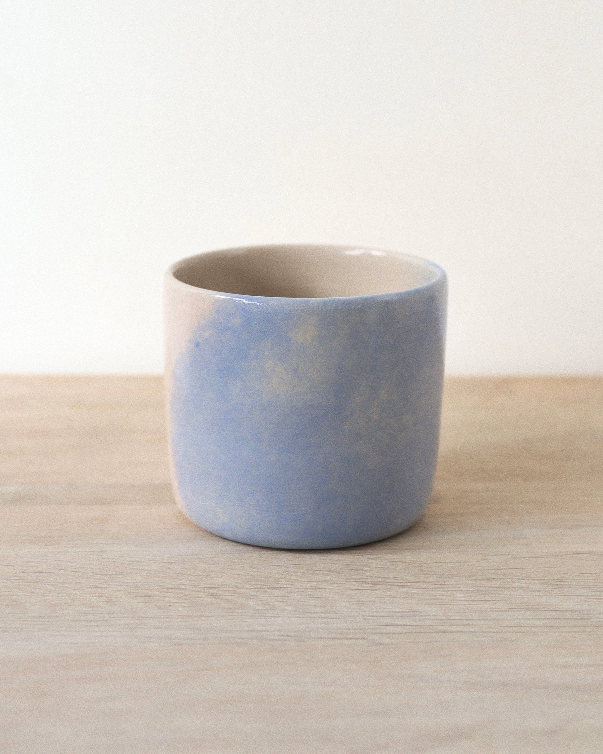 Cloud Cup – handmade white stoneware cup with soft pink and blue cloud-like underglazes and clear glaze, crafted in Amsterdam by Zeyah Ceramics.