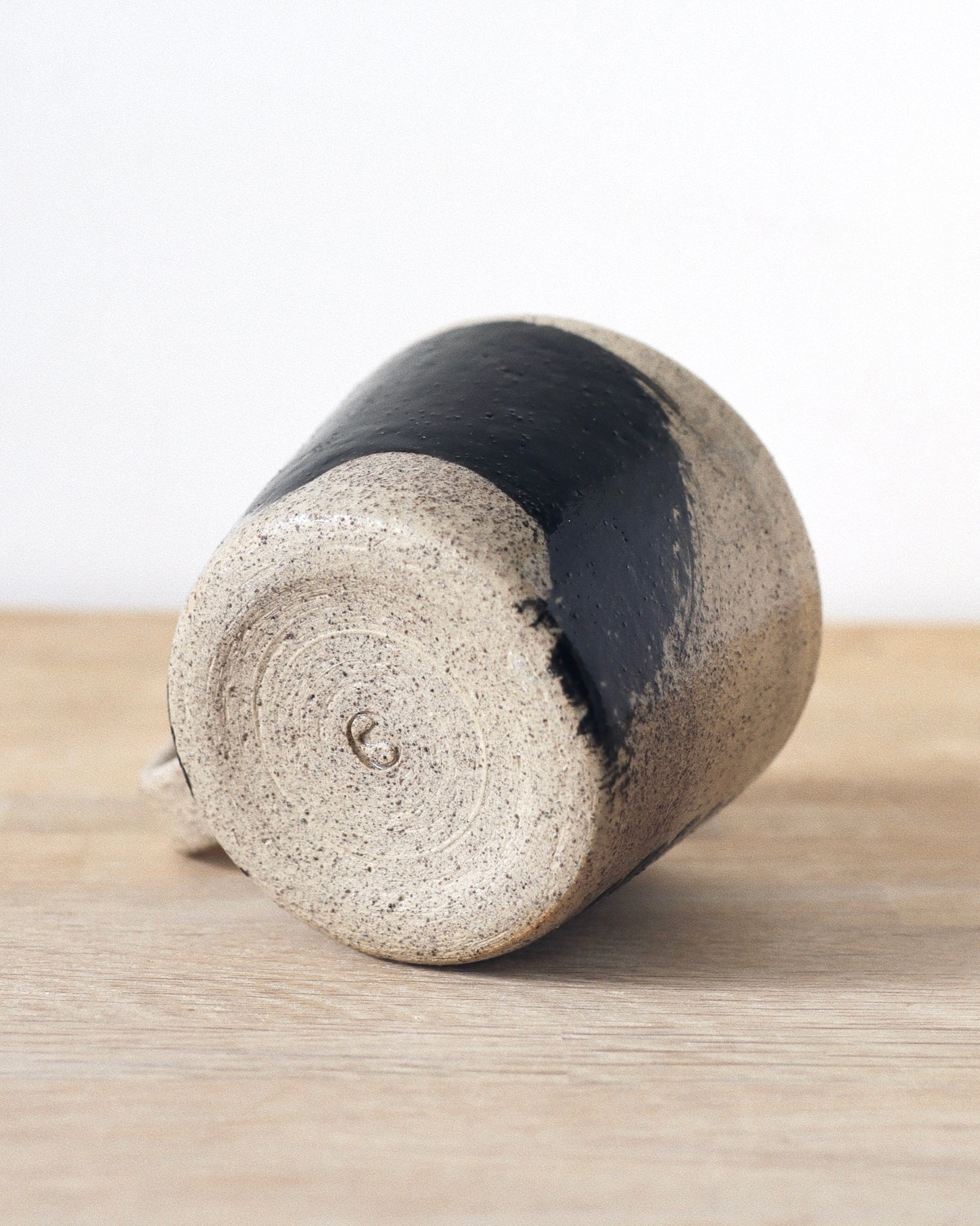 Grey Brush-Stroked Cup – handmade grey speckled stoneware cup with black brushstrokes and clear glaze revealing groggy texture, crafted in Amsterdam.