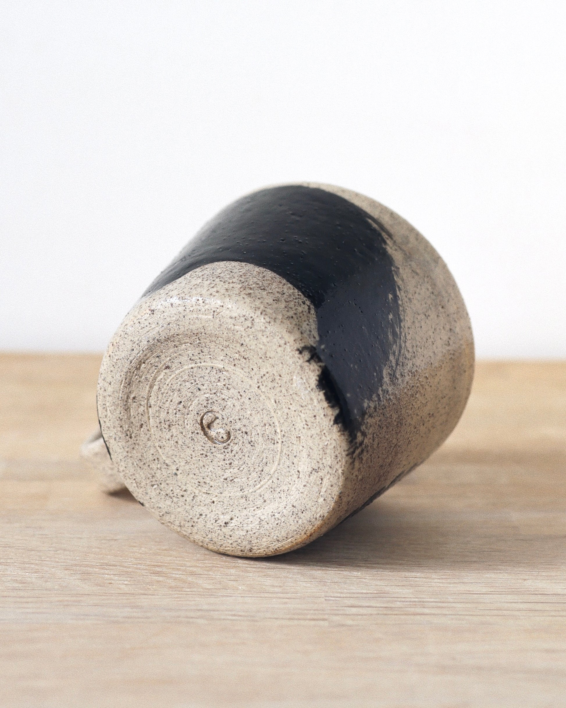 Grey Brush-Stroked Cup – handmade grey speckled stoneware cup with black brushstrokes and clear glaze revealing groggy texture, crafted in Amsterdam.