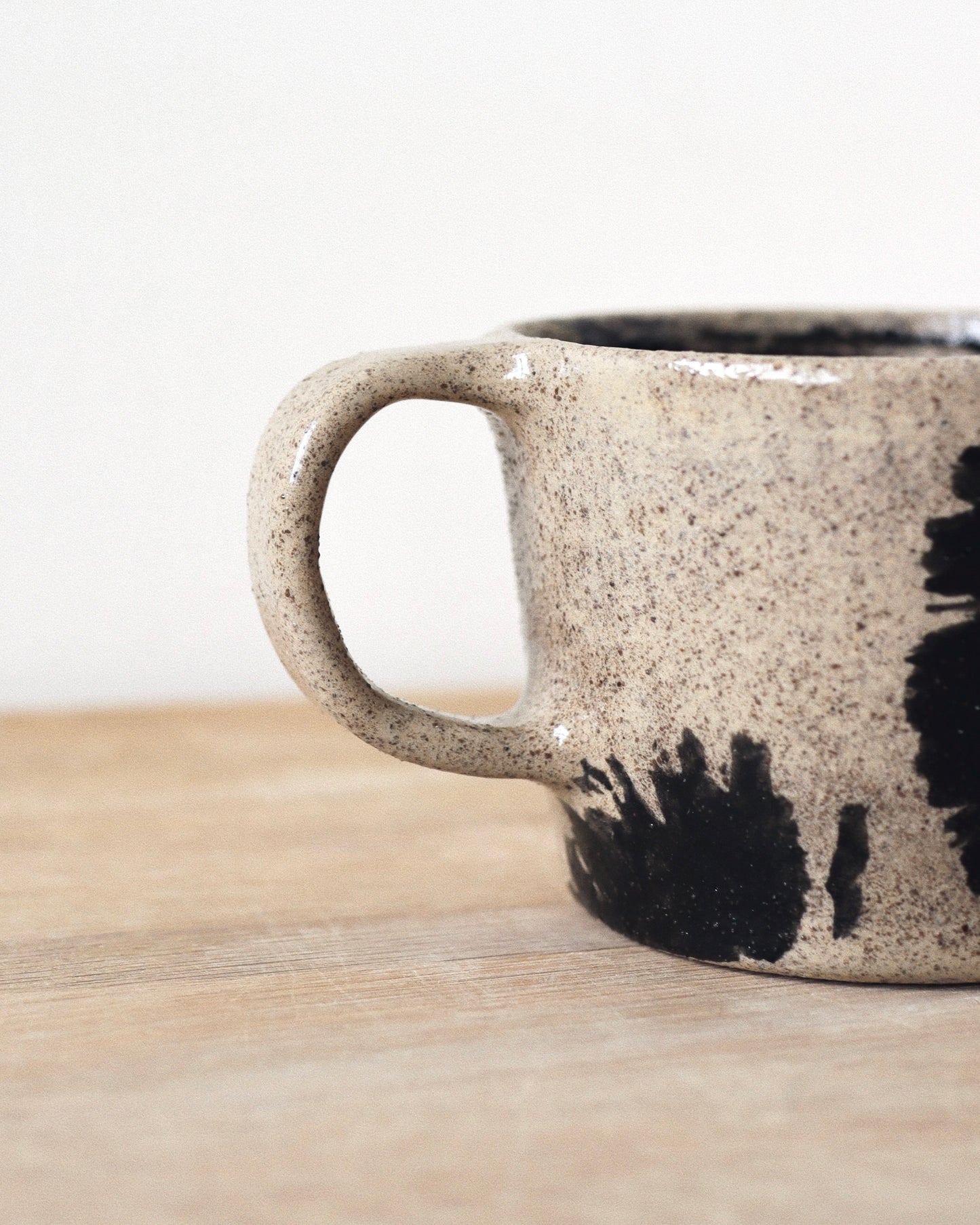 Grey Brush-Stroked Cup – handmade grey speckled stoneware cup with black brushstrokes and clear glaze revealing groggy texture, crafted in Amsterdam.