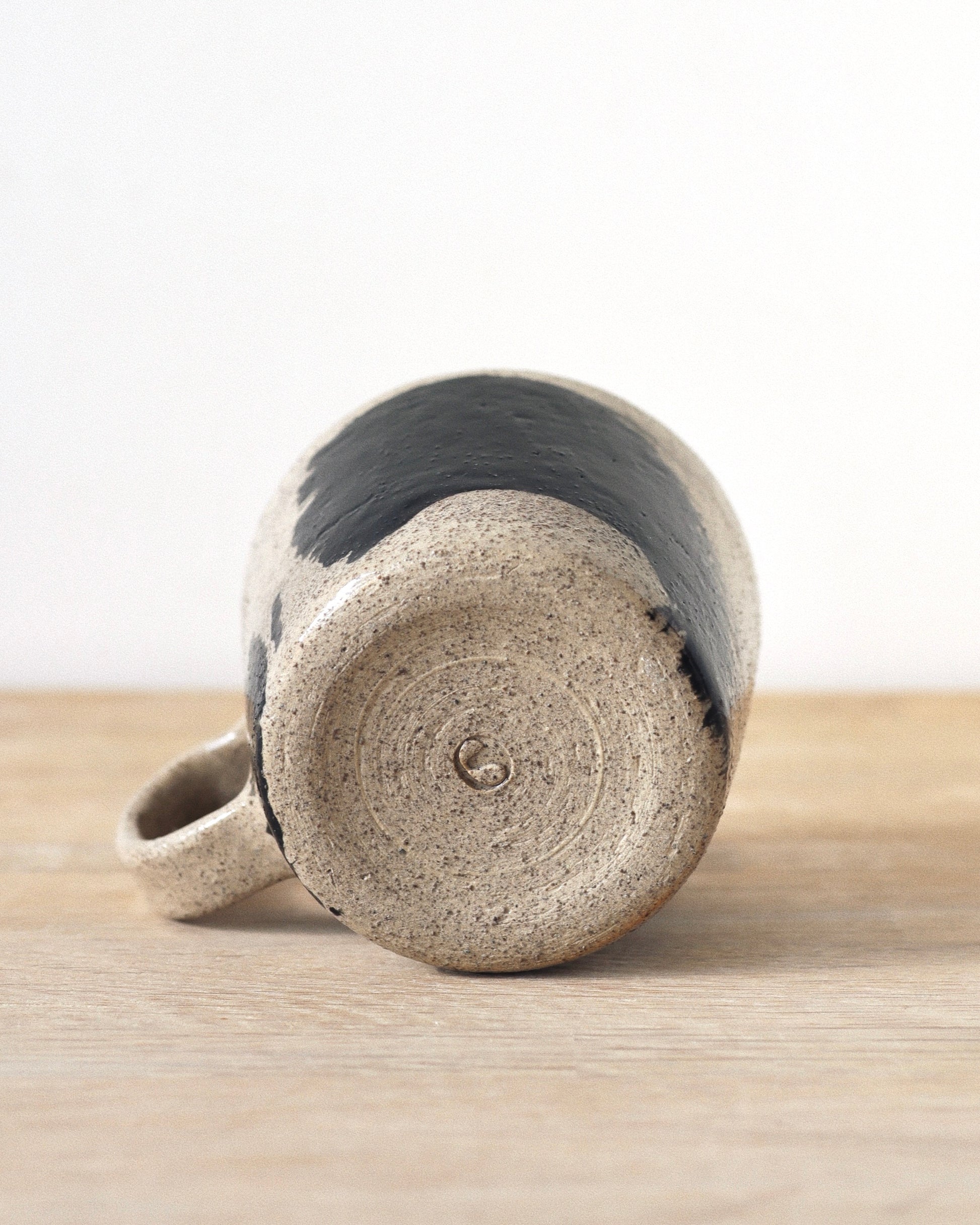 Grey Brush-Stroked Cup – handmade grey speckled stoneware cup with black brushstrokes and clear glaze revealing groggy texture, crafted in Amsterdam.