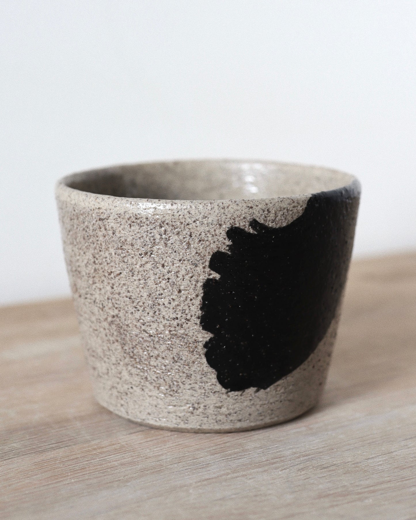 Grey Brush-Stroked Cup – handmade grey speckled stoneware cup with black brushstrokes and clear glaze, crafted in Amsterdam by Zeyah Ceramics.