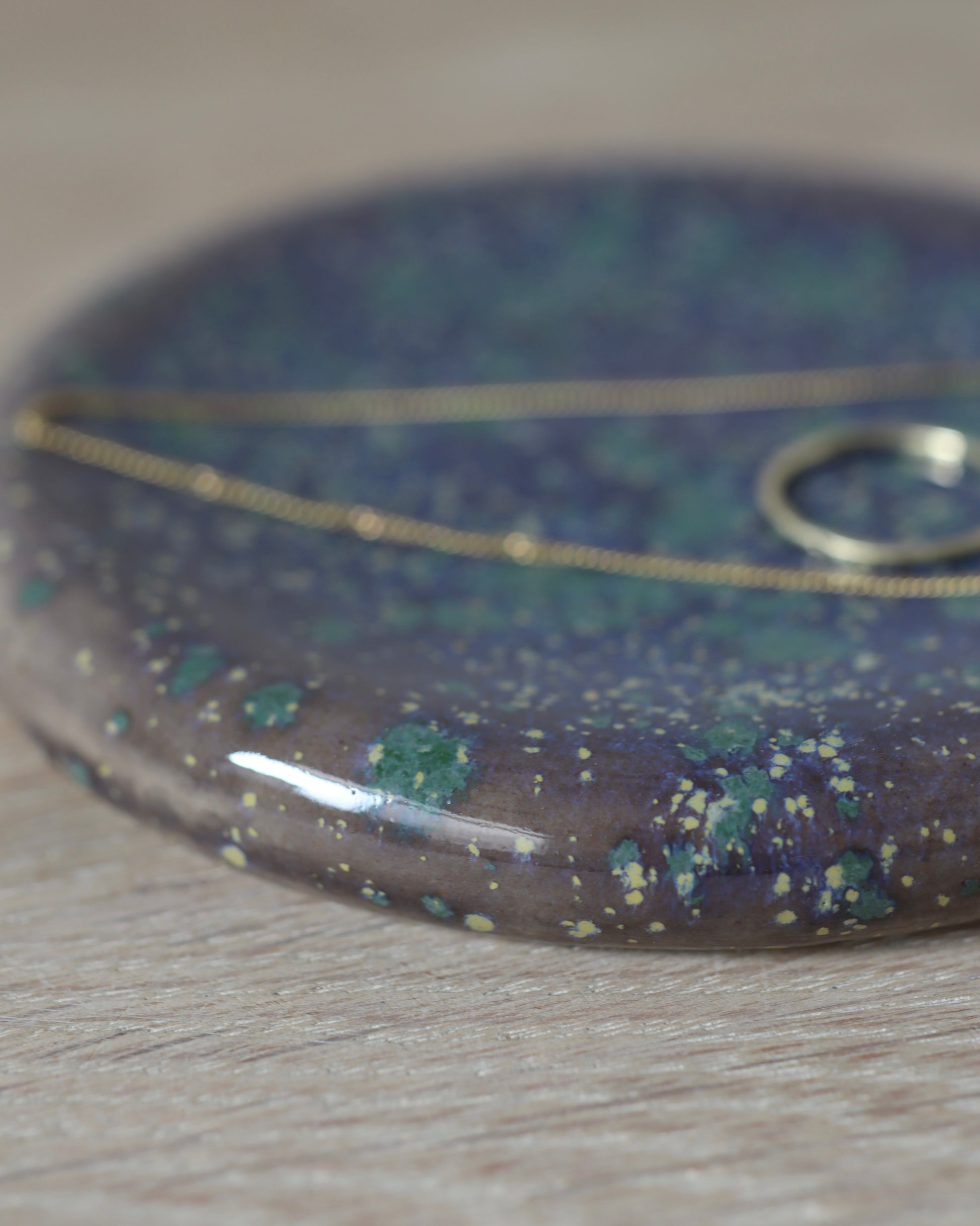 Mystic Jewelry Donut – handmade white stoneware dish with deep violet and green speckled glaze, crafted in Amsterdam by Zeyah Ceramics.