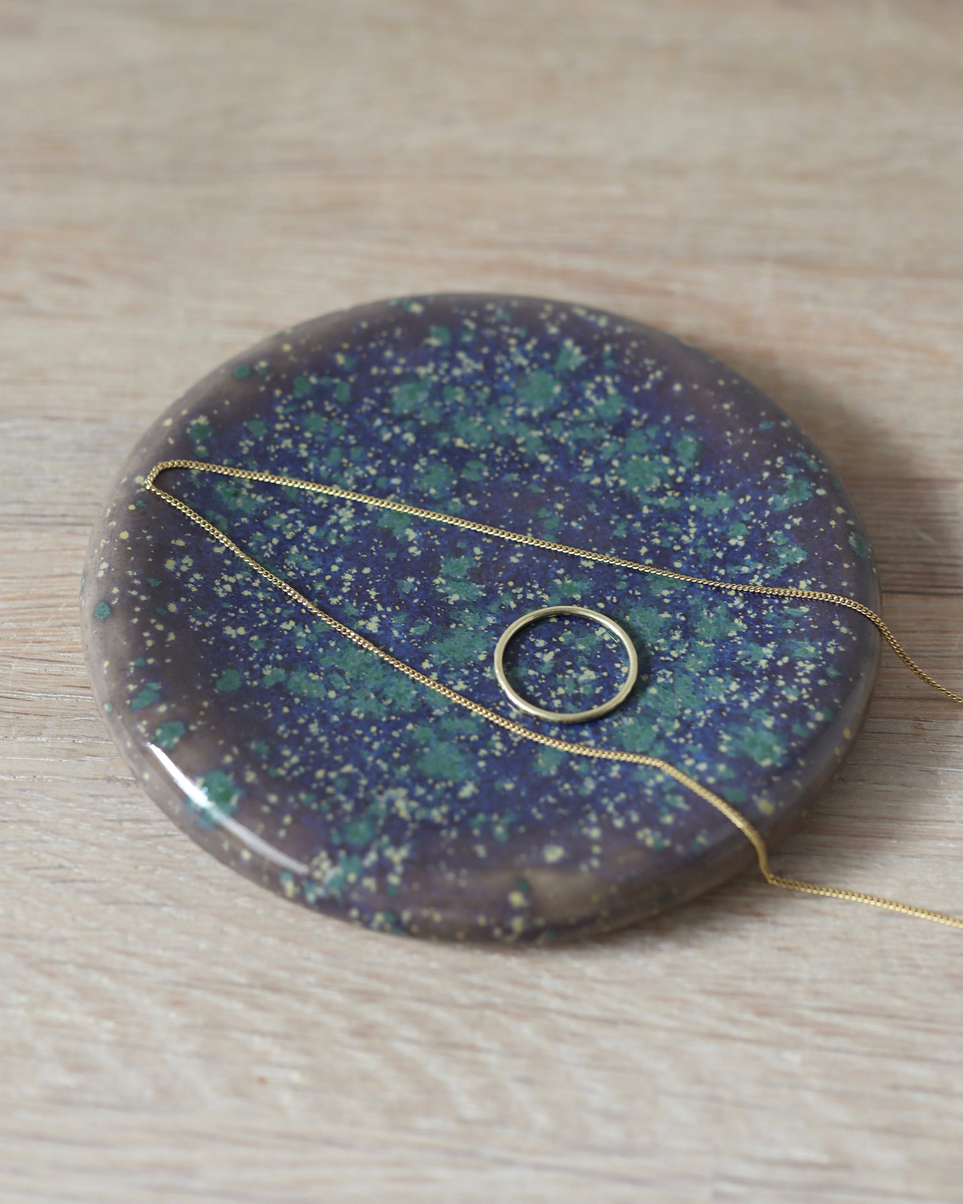 Mystic Jewelry Donut – handmade white stoneware dish with deep violet and green speckled glaze, crafted in Amsterdam by Zeyah Ceramics.