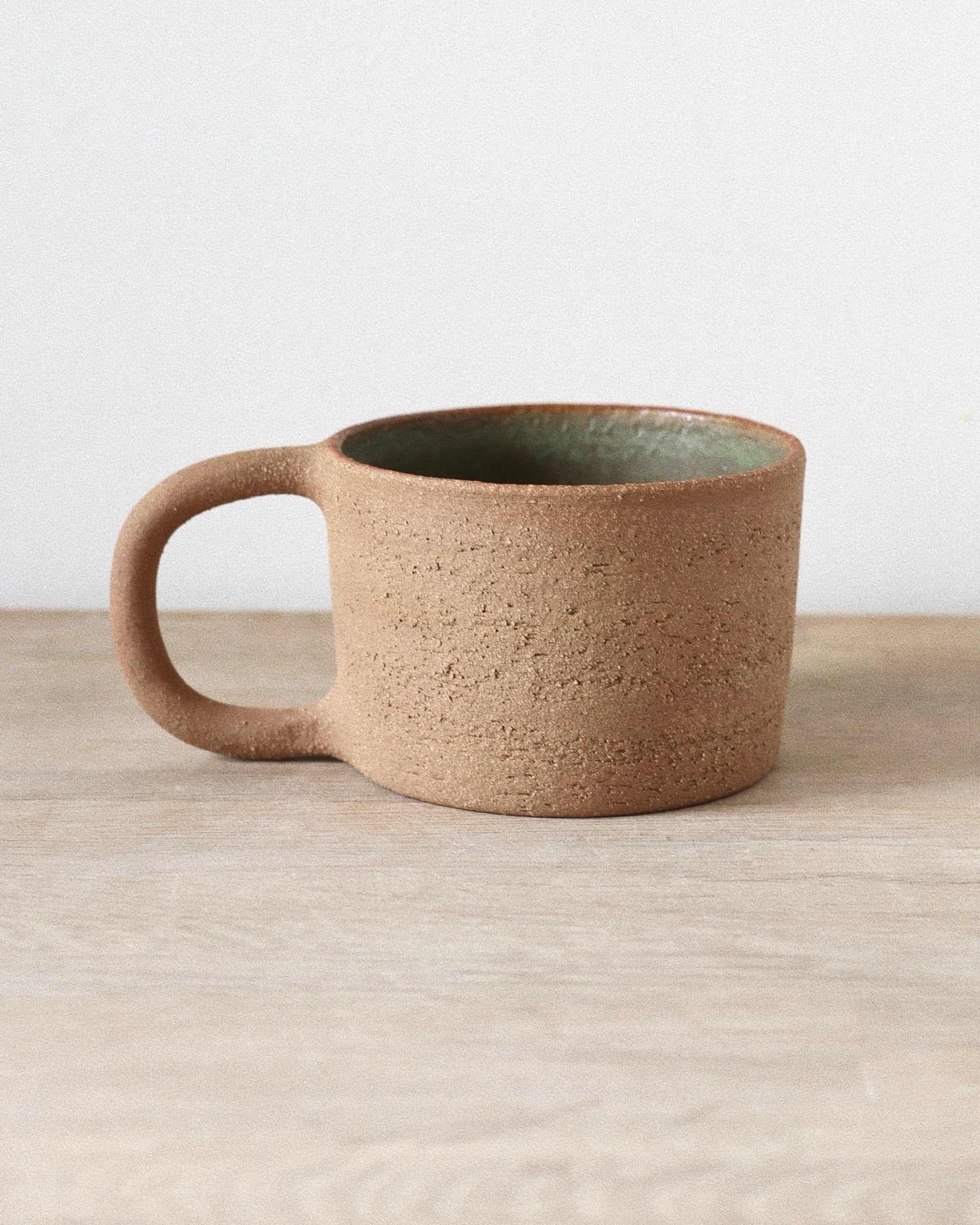 Rhea Mug – handmade red grogged stoneware mug with textured unglazed exterior and deep green glazed interior, crafted in Amsterdam by Zeyah Ceramics.