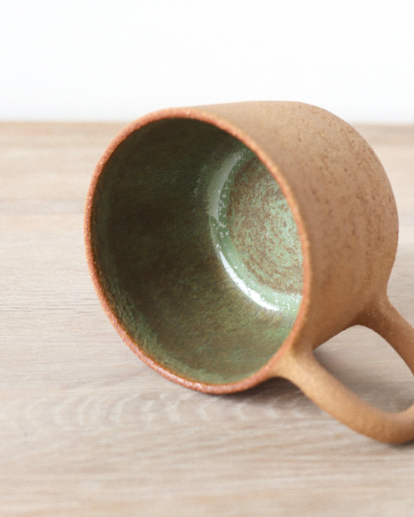 Rhea Mug – handmade red grogged stoneware mug with textured unglazed exterior and deep green glazed interior, crafted in Amsterdam by Zeyah Ceramics.