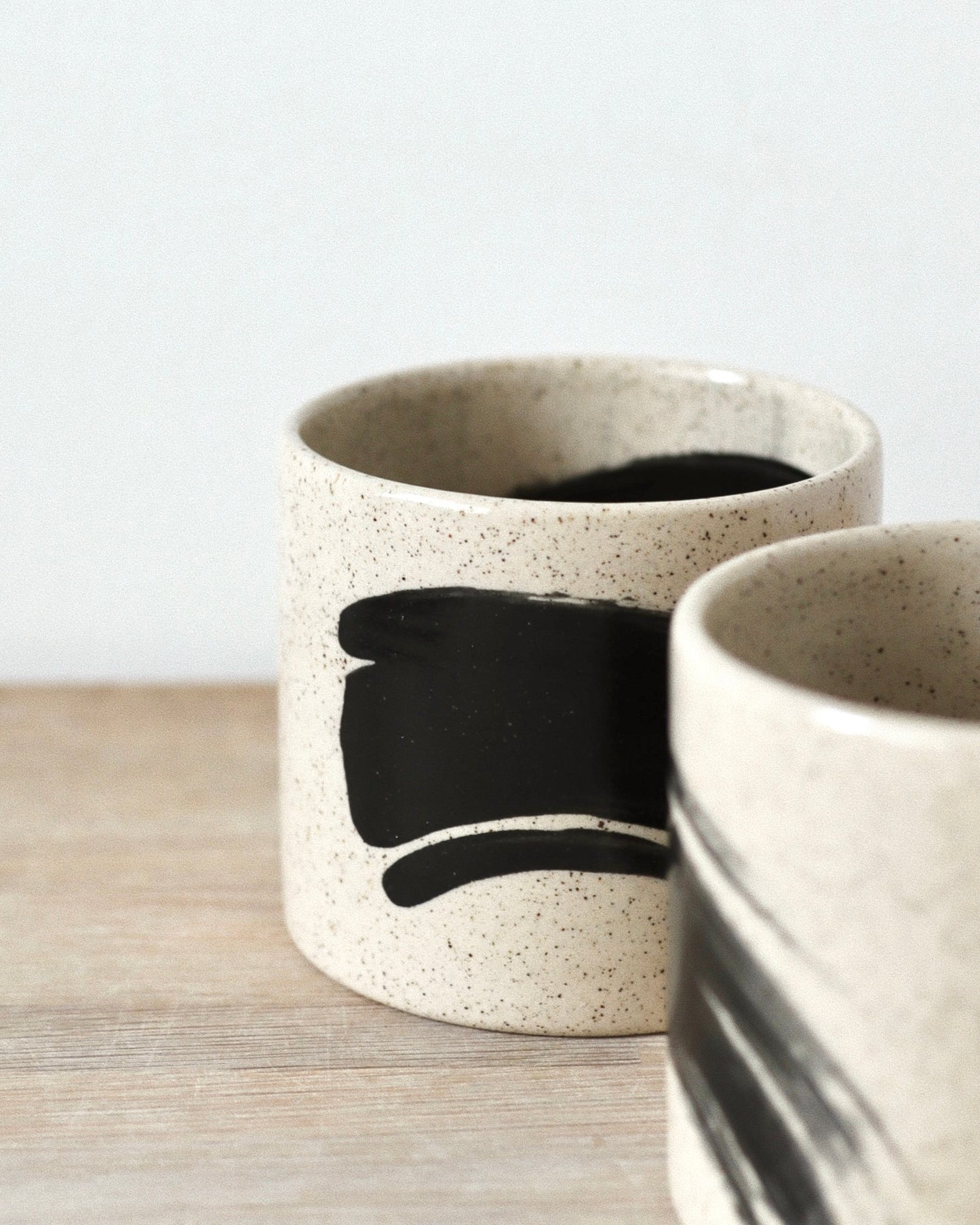 Speckled Brush-Stroked Set – handmade speckled white stoneware cup pair with expressive brush-strokes and clear glaze, crafted in Amsterdam by Zeyah Ceramics.
