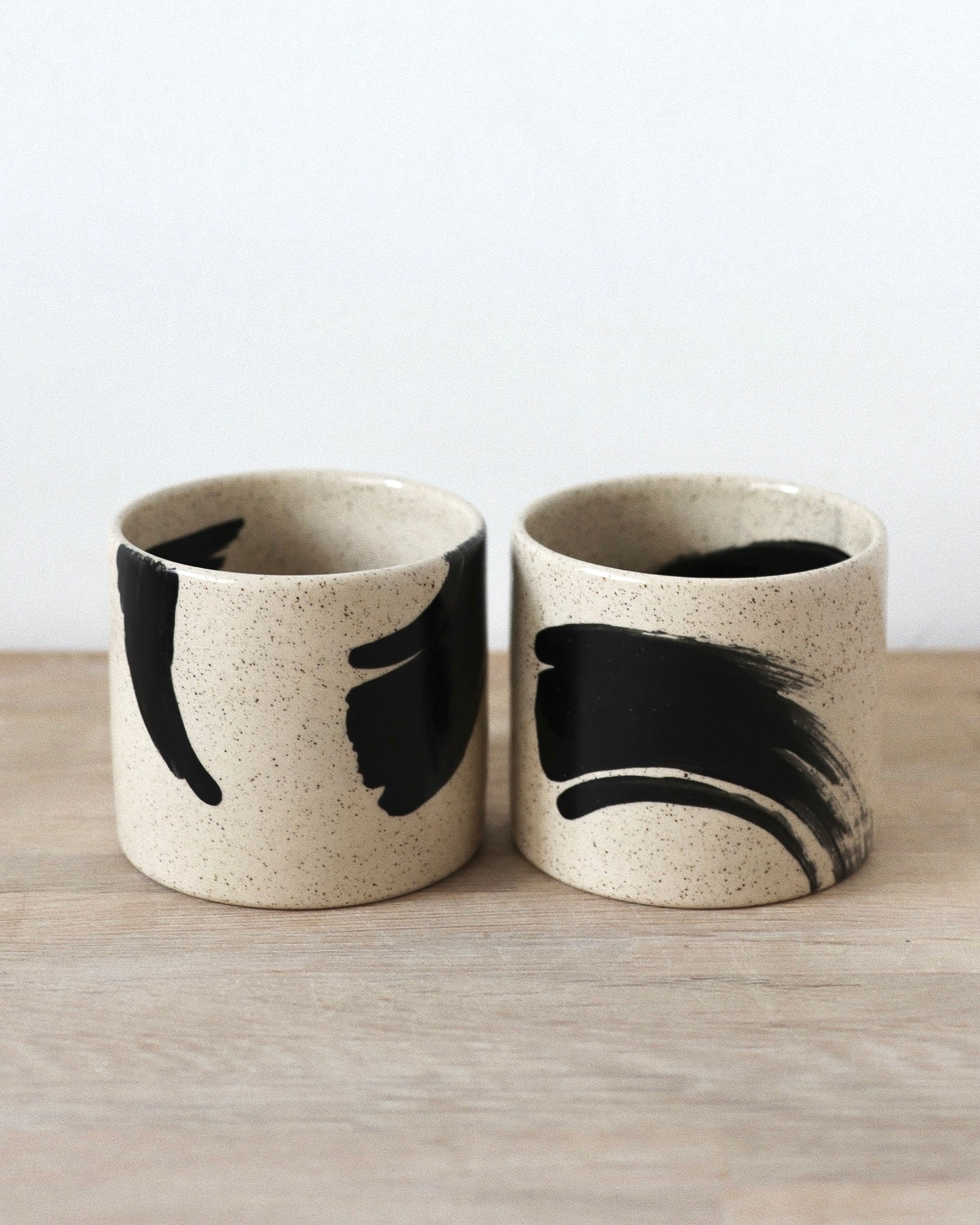 Speckled Brush-Stroked Set – handmade speckled white stoneware cup pair with expressive brush-strokes and clear glaze, crafted in Amsterdam by Zeyah Ceramics.