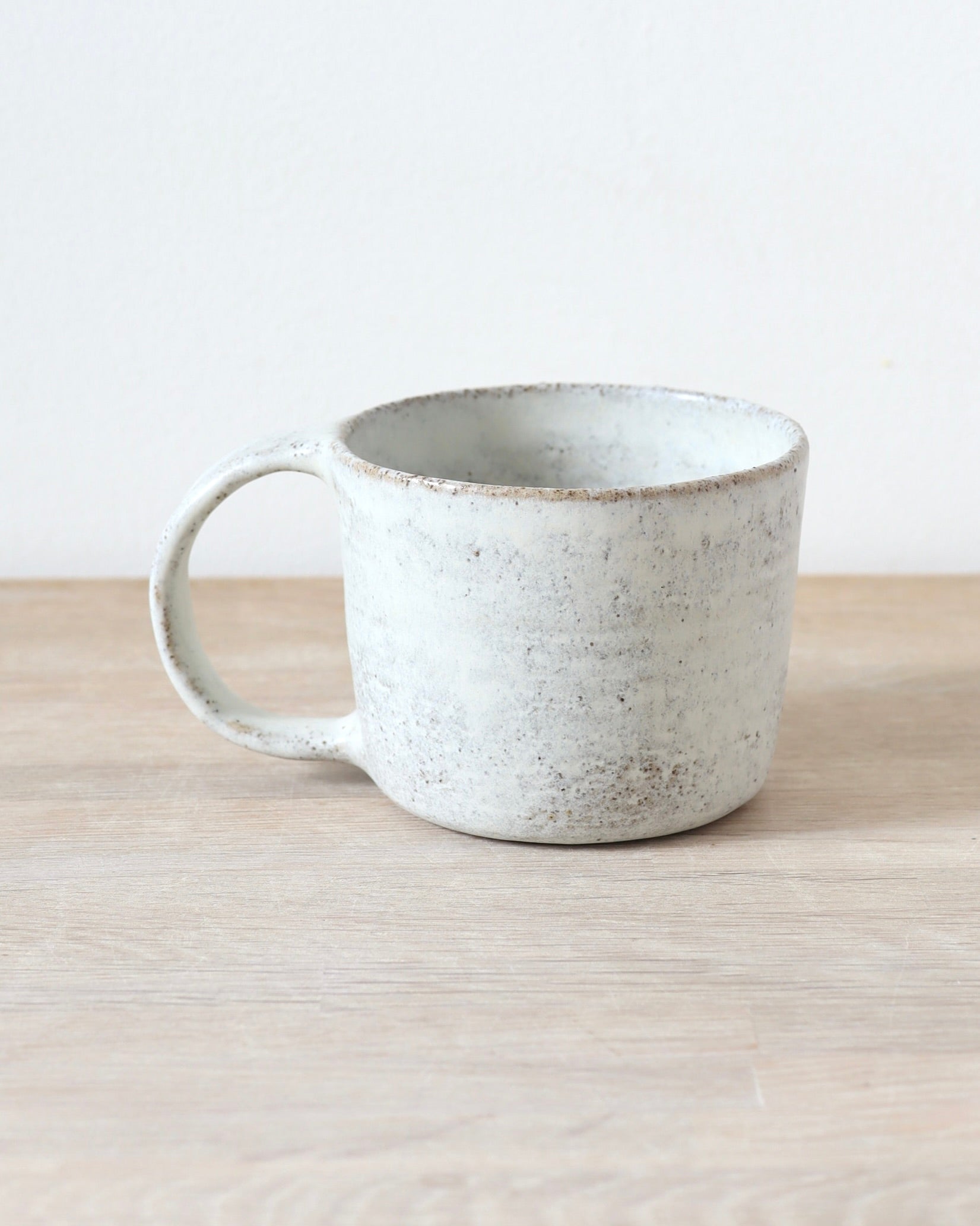 Grey speckled stoneware cup with matte white glaze, handmade by Zeyah Ceramics in Amsterdam.