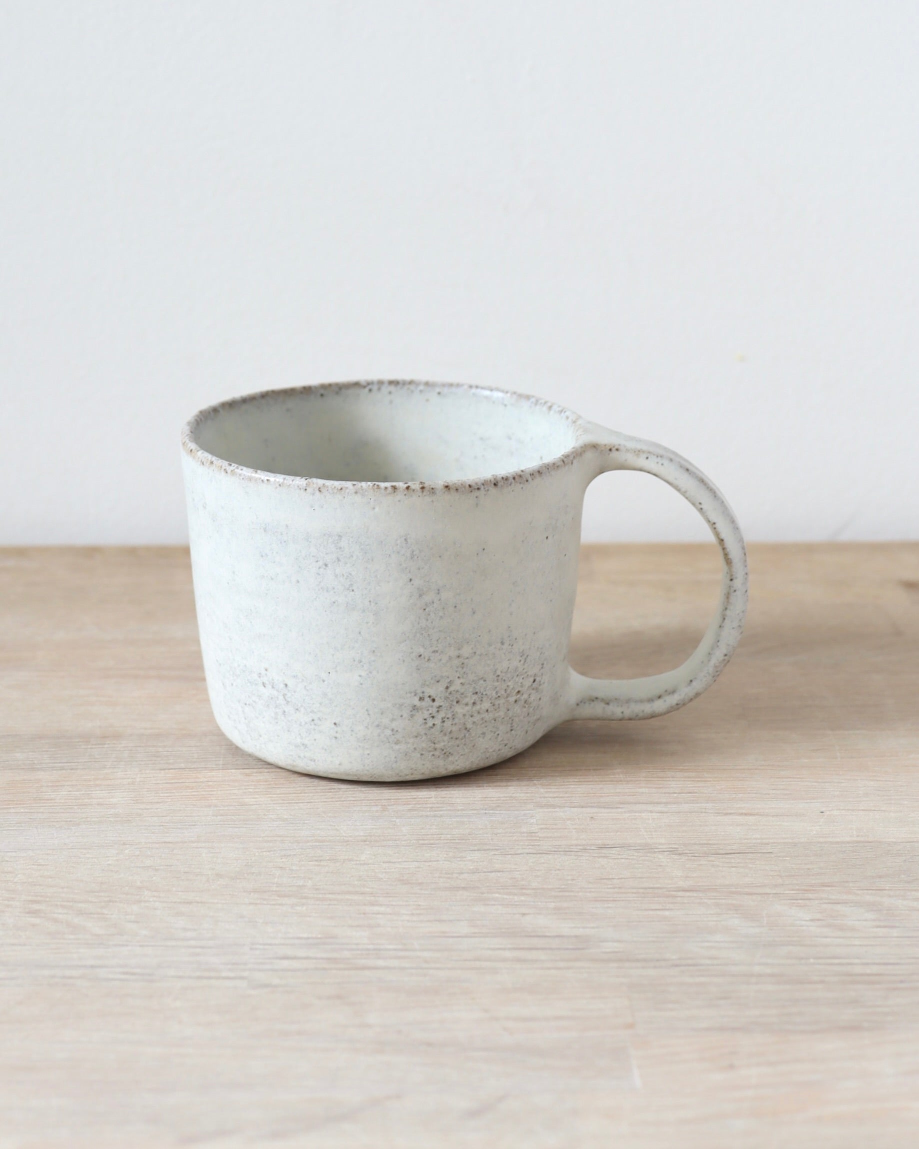 Grey speckled stoneware cup with matte white glaze, handmade by Zeyah Ceramics in Amsterdam.