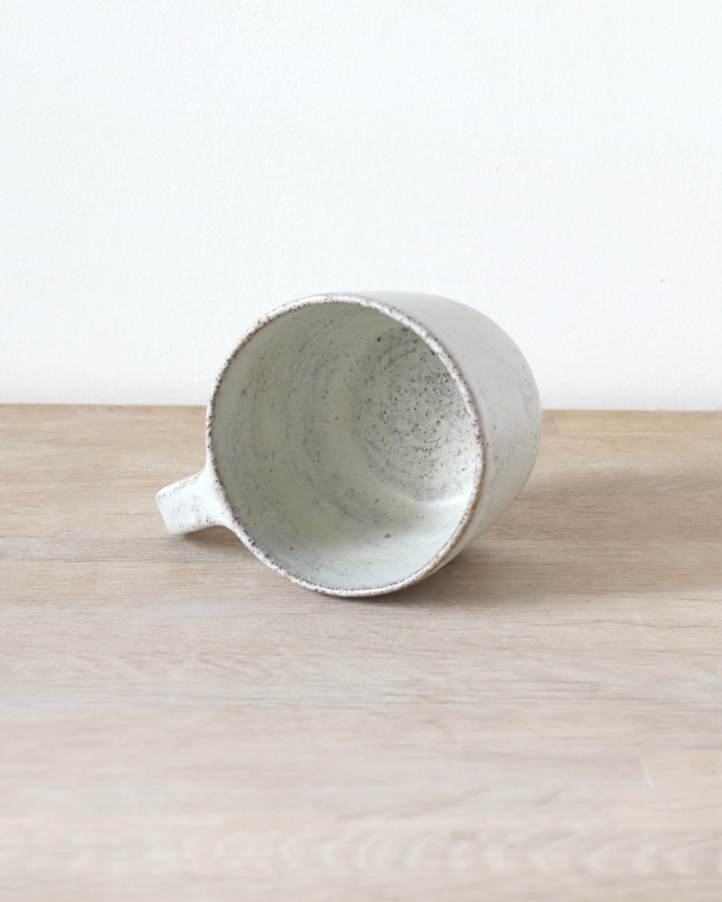 Grey speckled stoneware cup with matte white glaze, handmade by Zeyah Ceramics in Amsterdam.
