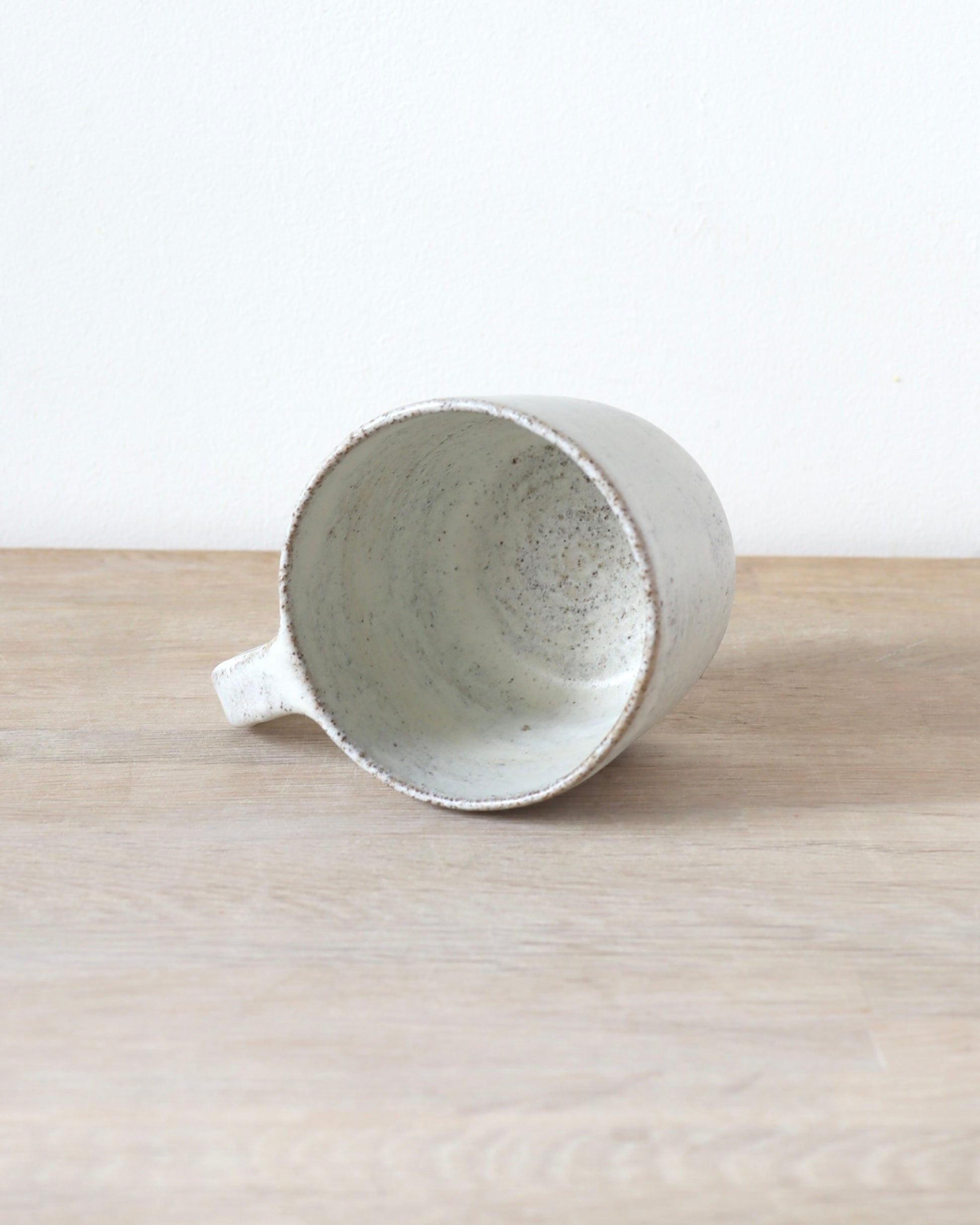 Grey speckled stoneware cup with matte white glaze, handmade by Zeyah Ceramics in Amsterdam.