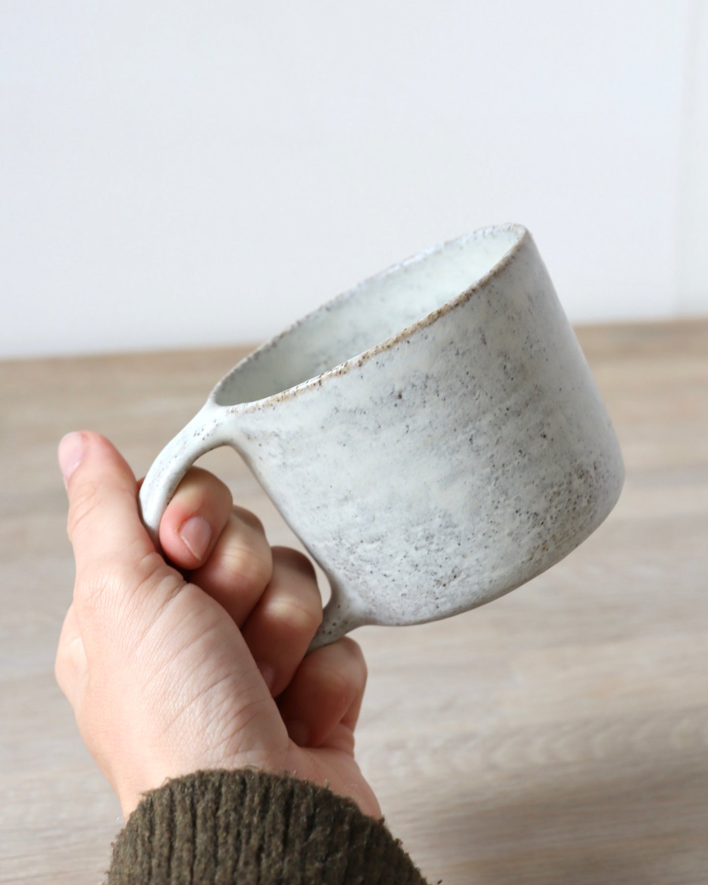 Grey speckled stoneware cup with matte white glaze, handmade by Zeyah Ceramics in Amsterdam.