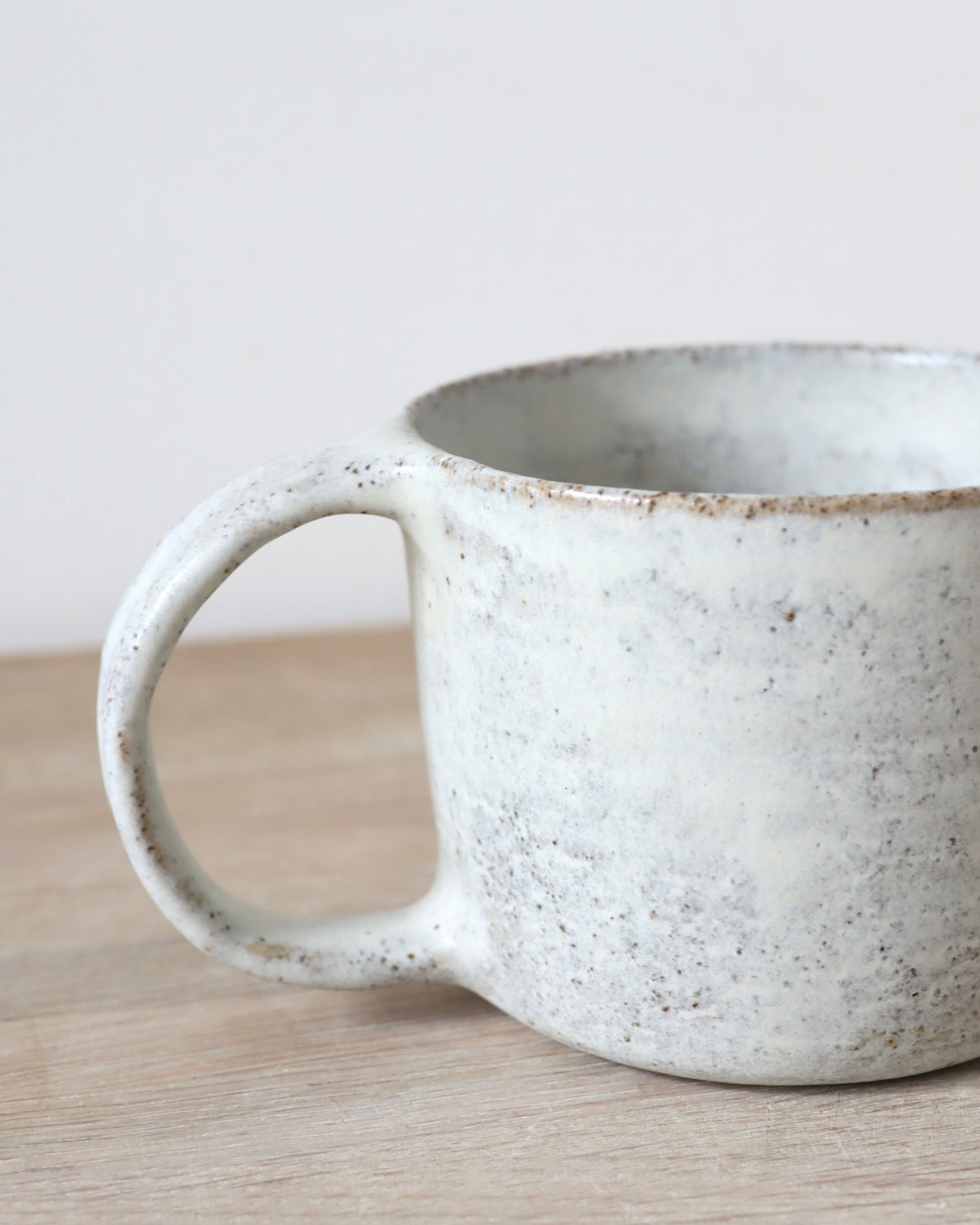 Grey speckled stoneware cup with matte white glaze, handmade by Zeyah Ceramics in Amsterdam.